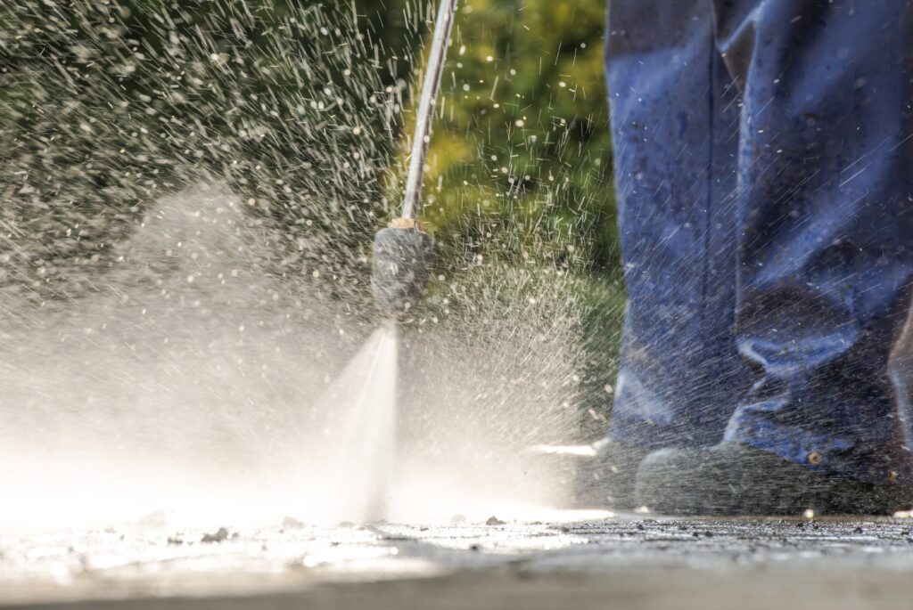 worker cleaning with power washer outside on concr 2026 03 24 00 32 05 utc