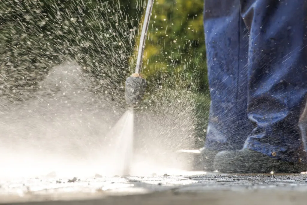 worker cleaning with power washer outside on concr 2026 03 24 00 32 05 utc